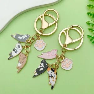 Detail van schattige emaille kattenhangers aan een gouden sleutelhanger met pootafdruk