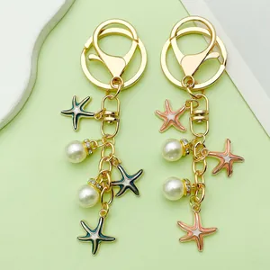 Detailed view of handmade gold starfish and pearl enamel keychains in teal and pink colors.