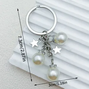 Elegante zilveren metalen sleutelhanger met drie parels en twee sterren, 7,3 cm groot.