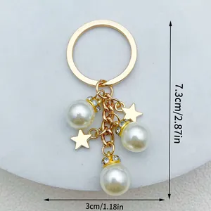 Handgemaakte gouden sleutelhanger met witte parels en sterren, afmeting 7,3 cm x 3 cm