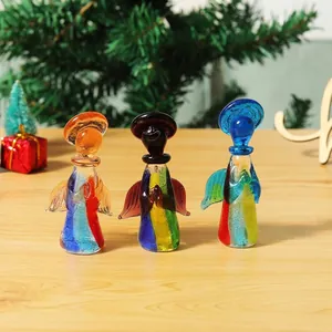 Tres figuritas de ángeles de cristal de colores hechas a mano en una mesa de madera