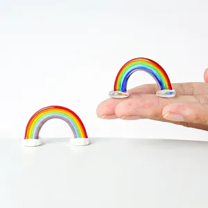 Detail of miniature glass rainbow figurines showing scale and craftsmanship on fingertips