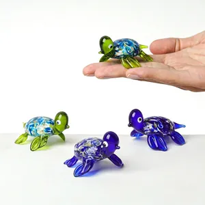 Hand showing the scale of a miniature colorful glass sea turtle figurine for decor