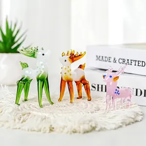 Detailed view of three colorful handmade glass deer figurines on a white woven mat