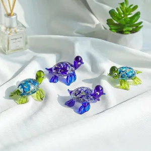 Macro view of colorful hand-blown glass sea turtle figurines on white fabric.