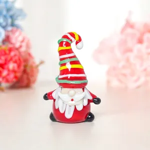 Gros plan d'une figurine de Père Noël en verre avec un bonnet rayé coloré pour Noël.