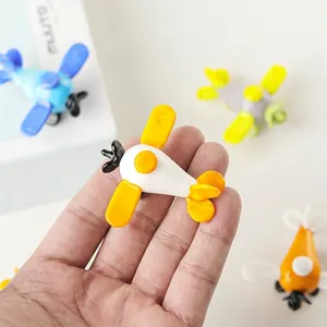 Detalle de un modelo de avión de vidrio en miniatura sostenido en mano para la escala.