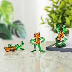 Close-up of three miniature handmade glass frog figurines in playful dancing poses.