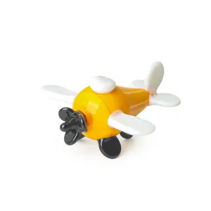 Detalle de una figurita de avión de vidrio amarilla y blanca hecha a mano, brillante