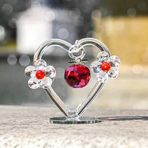 Gros plan détaillé d'un ornement en cœur de cristal avec pomme rouge et fleurs