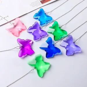 Vue détaillée de pendentifs attrape-soleil papillon en cristal coloré avec chaînes argentées