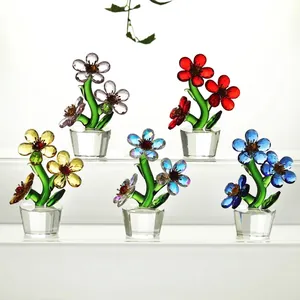 Collection de cinq figurines de fleurs en cristal colorées dans des pots sur support blanc