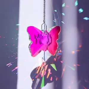 Détail d'un attrape-soleil en cristal papillon rose avec des reflets arc-en-ciel.