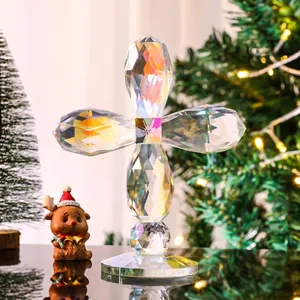 Iridescent multi-faceted crystal cross ornament shown in a festive holiday setting.