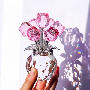 Elegante adorno de rosa de cristal rosa sostenido a mano con base de luz arcoíris.
