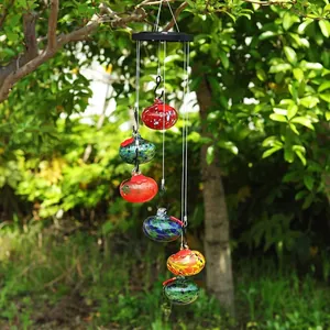 Vue détaillée d'ornements en verre coloré sur un carillon solaire dans un jardin vert