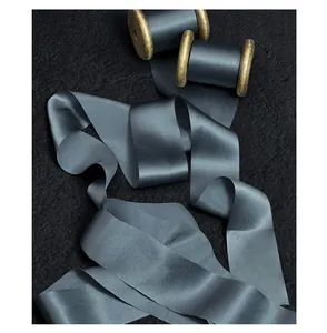 Detailed view of glossy steel blue silk raw-edge ribbon with vintage wooden spools