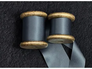 Close-up detail of high-quality dark grey raw edge silk ribbon on vintage wooden spools