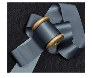 Detailed macro view of luxurious charcoal gray silk raw-edge ribbon on a wooden spool
