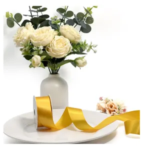 Macro view of silky golden satin ribbon displayed elegantly on a white porcelain plate