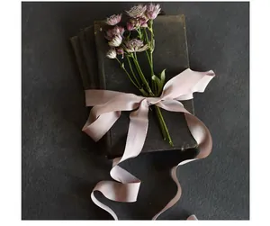 Close-up of elegant pink silk ribbon with raw edges tied on a vintage book for decor