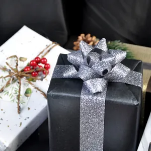 Elegante zilveren glitterlintstrik op zwarte doos voor luxe kerstcadeauverpakkingen.