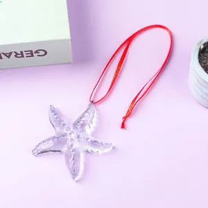 Detail view of transparent glass starfish ornament with blue dots and red string