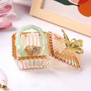 Detailed view of an amber glass jewelry box with a butterfly lid and jewelry inside