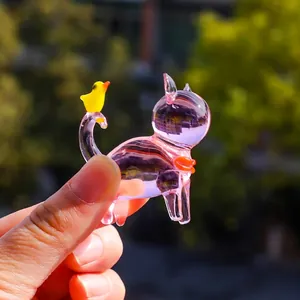 Detailed view of miniature pink crystal cat figurine with yellow bird ornament.