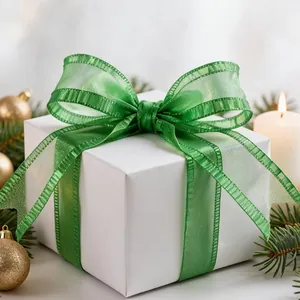 Elegant green ruffled crepe chiffon ribbon tied in a bow on a white Christmas gift box