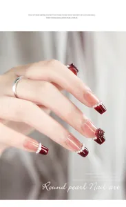 Primo piano di unghie rosse decorate con eleganti perle bianche di varie dimensioni