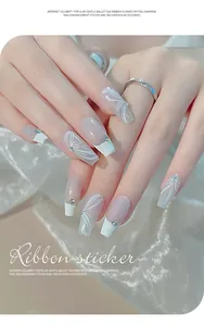 Macro shot of 3D embossed ribbon nail stickers with rhinestones on white French tips.