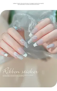 Detailed macro view of 3D white ribbon embossed nail stickers and sparkling rhinestones