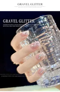 Gedetailleerde close-up van nagelkunst met dromerige glitter en schelpschilfers