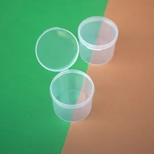 Two clear round PP plastic containers with flip-top lids on a green and tan background