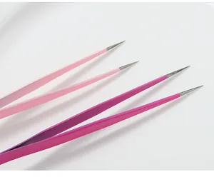 Primo piano di pinzette di precisione per nail art professionale nei toni del rosa.