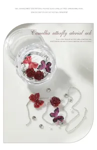 Detailed view of camellia and bow nail art accessories with silver chains and pearls