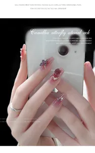 Detail shot of 3D camellia and butterfly charms on pink gradient nails.
