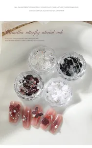 Detail view of 3D camellia and butterfly nail charms in clear jars with finished nails.