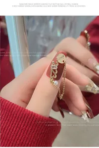 Gros plan d'un bijou d'ongle doré 2023 avec zircone, perle et pendentif Fu chinois