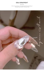 Close-up of 3D bow nail charm with shiny zircons and pearls on long nails.