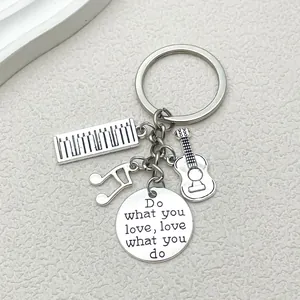 Close-up of music-themed keychain with guitar, piano, and inspirational round charm.