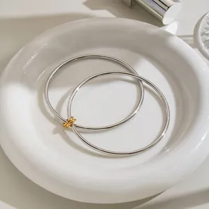 Detailansicht eines minimalistischen doppellagigen Edelstahl-Armreifs in einer Keramikschale.
