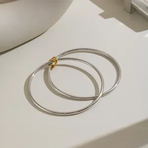 Nahaufnahme minimalistischer silberner Armreifen mit goldenen Verbindungsringen