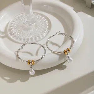 Detailed view of silver stainless steel hoop earrings featuring white pearl pendants