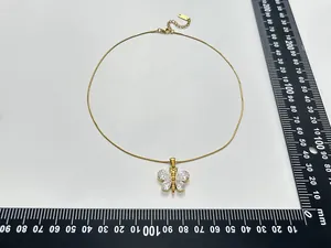 Macro detail of gold-plated butterfly necklace with zircon inlay and measurement rulers
