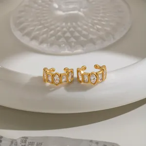 Detailed macro view of vintage geometric zircon ear cuffs featuring a luxury gold finish