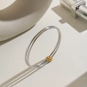 Nahaufnahme eines minimalistischen doppelreihigen Edelstahl-Armreifs mit Goldakzenten