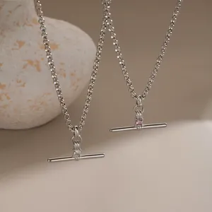 Detailed close-up of T-bar pendants with square clear and pink zircons on steel chains.