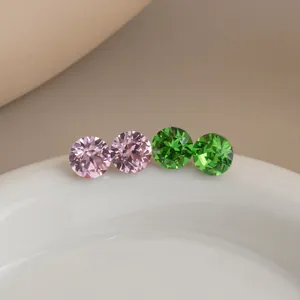 Close-up of pink and green faceted crystal glass stud earrings on a ceramic dish